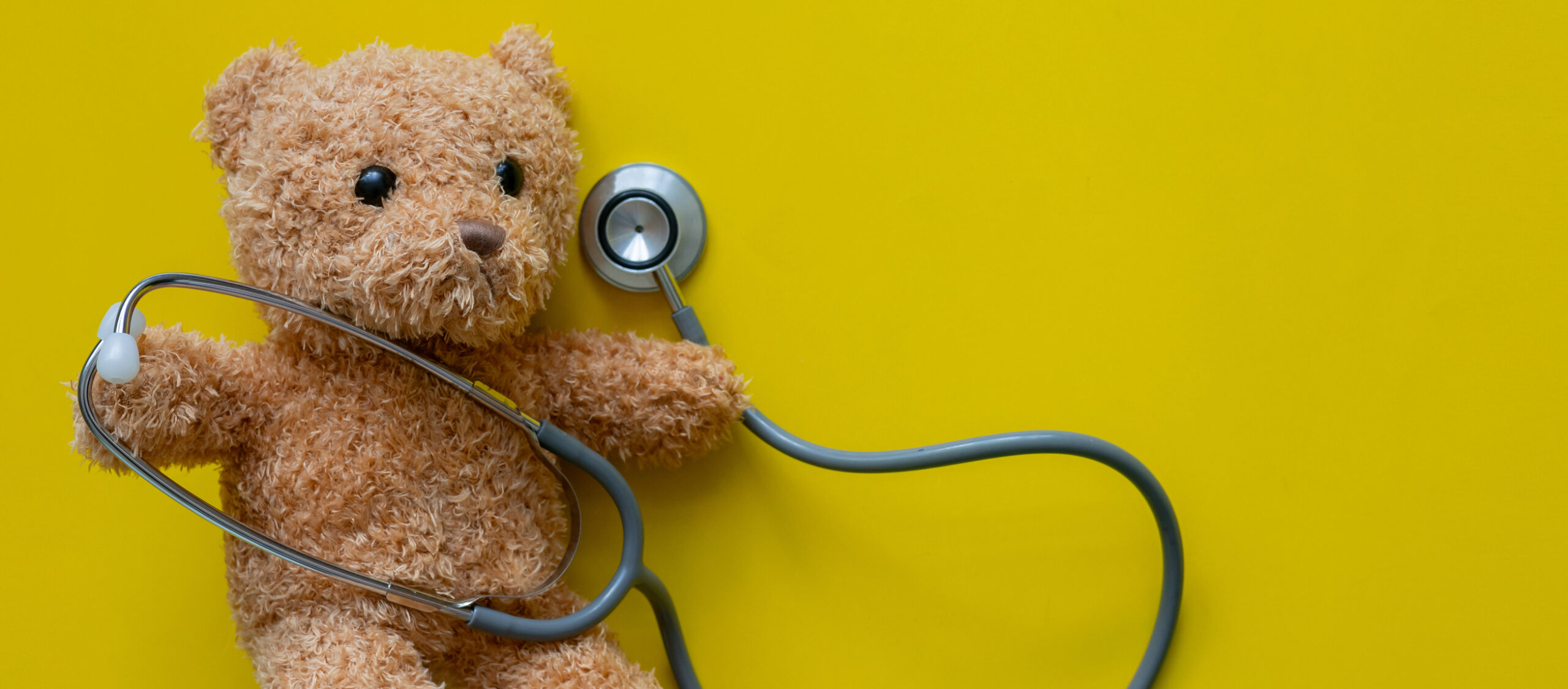 Teddy bear with stethoscope on yellow. Pediatric surgery